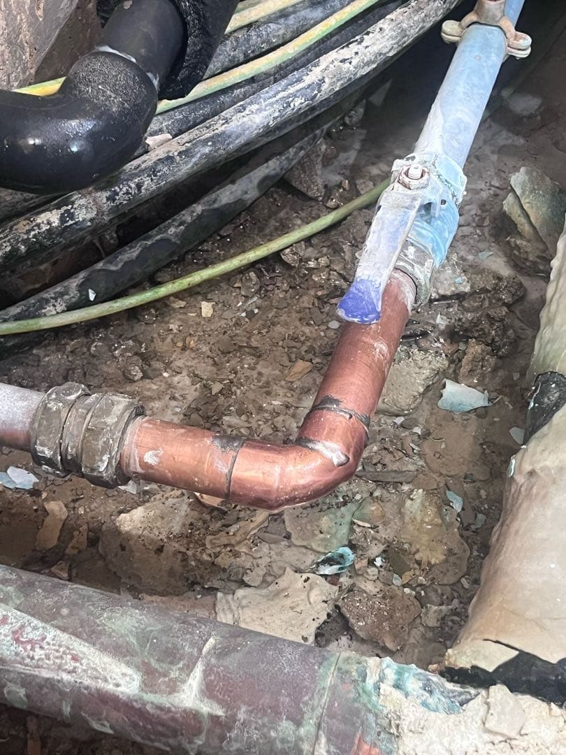 Exposed copper pipework and a blue-handled valve beneath the care-home floor